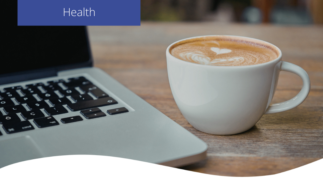 a coffee next to a laptop in the office